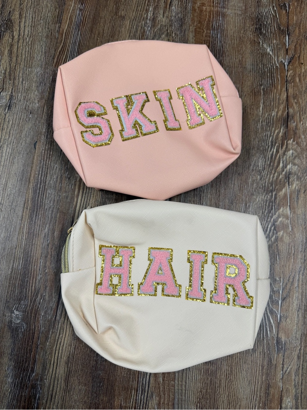 Pink and cream makeup bags with pink lettering spelling 'SKIN' and 'HAIR'